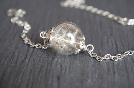 Bracelet nature en verre soufflé – vraie graine de pissenlit enfermée dans une perle creuse tournante, monture argentée réglable. Élégance légère et rêveuse.