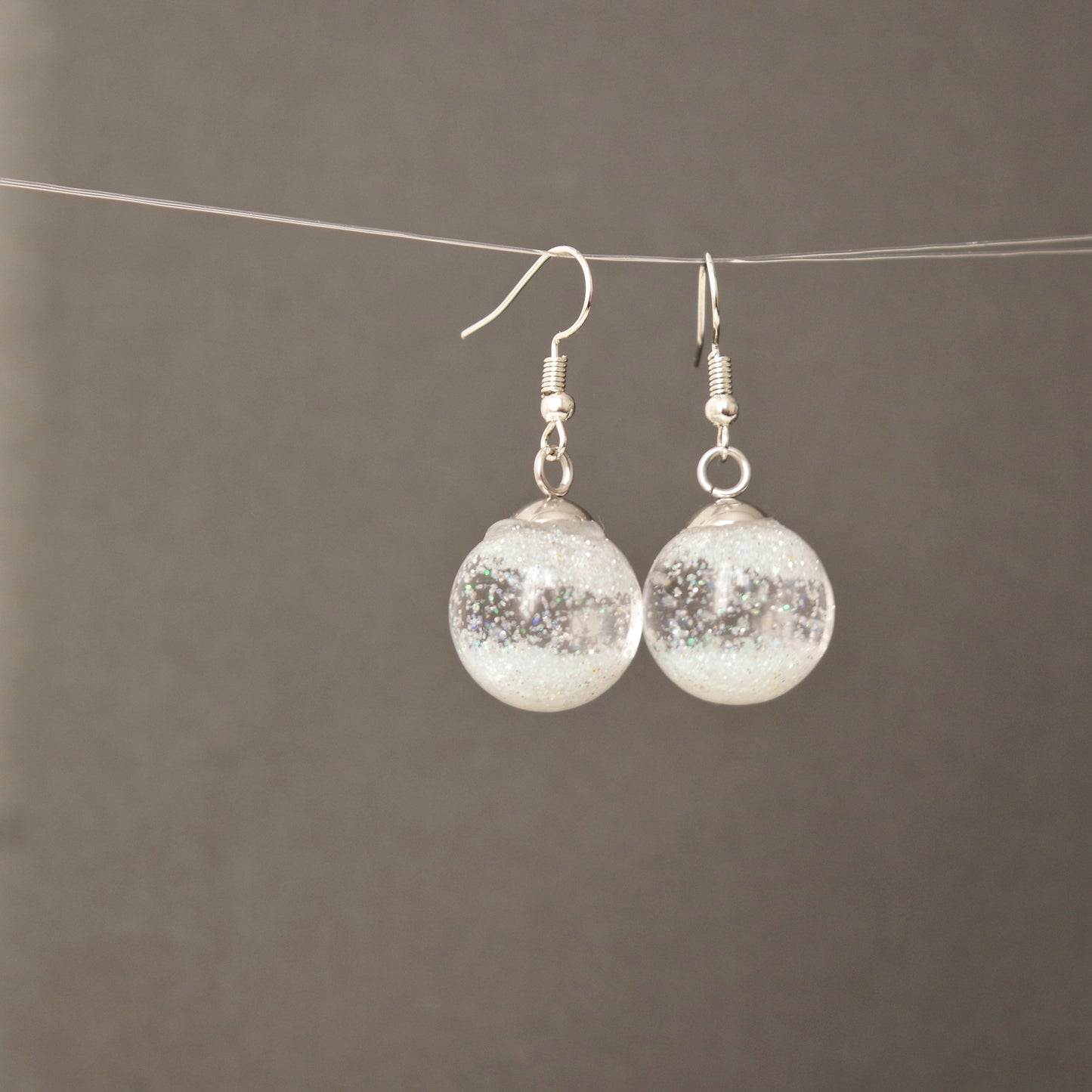 Boucles d’oreilles globe en verre transparent avec flocons de neige en suspension, effet boule à neige, bijou hivernal élégant pour femme.