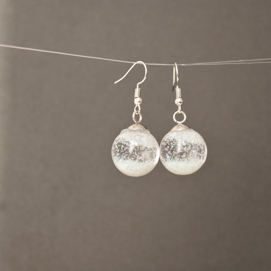 Boucles d’oreilles globe en verre transparent avec flocons de neige en suspension, effet boule à neige, bijou hivernal élégant pour femme.